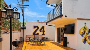 A patio area with a wooden deck, outdoor seating, a barbecue grill, and a large number '24' on a wall. - Kobe Bryant vacation getaway - 5 minutes to Rodeo Drive, Game console, Hot Tub (Beverly Hills)