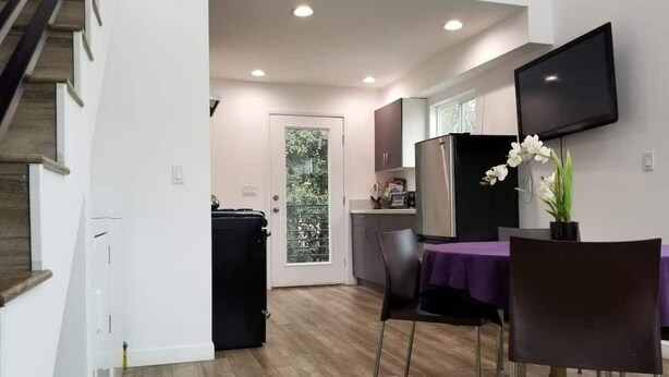 A modern kitchen with a dining area, wooden flooring, and a flat-screen TV mounted on the wall. - Kobe Bryant vacation getaway - 5 minutes to Rodeo Drive, Game console, Hot Tub (Beverly Hills)