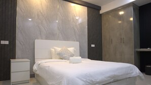 Une chambre moderne avec un grand lit, des tables de chevet blanches et des armoires encastrées.