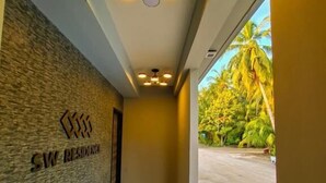 Un couloir avec une enseigne indiquant « SW RESIDENCE » et un plafond orné de luminaires circulaires.