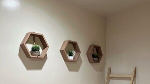 A room with three hexagonal wall shelves, each holding a plant. A wooden ladder is leaning against the wall. - El Nido Loft Apartment (El Nido)