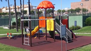 Une aire de jeux avec un toboggan, des structures d’escalade et un espace abrité.