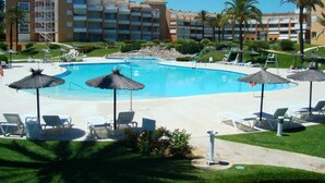 Un hôtel doté d’une grande piscine entourée de chaises longues et de parasols.
