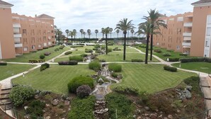 Une cour d’hôtel agrémentée d’une fontaine centrale, entourée de pelouses bien entretenues et de palmiers.