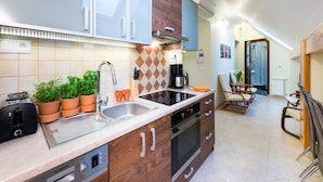 A modern kitchen with a Bosch dishwasher, a coffee maker, and potted plants. There is a dining area with a table and chairs. - Vanilla 3, 4bdr 2bth apartment 5min to Krakow's Main Square (Kraków)