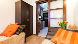 A small bedroom with two beds, a wooden wardrobe, a small kitchen area, and a window with frosted glass panels. - Vanilla 3, 4bdr 2bth apartment 5min to Krakow's Main Square (Kraków)
