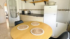 A modern kitchen with a round wooden table, black chairs, and a white refrigerator. - Cozy & Spacious apartment near the old town of Tarifa. (Tarifa)