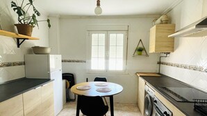 A compact kitchen with a dining table, a washing machine, and a refrigerator. - Cozy & Spacious apartment near the old town of Tarifa. (Tarifa)