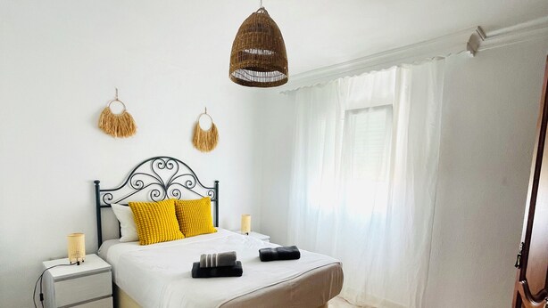 A bedroom with a bed, bedside tables, a hanging lamp, and a window with curtains. - Cozy & Spacious apartment near the old town of Tarifa. (Tarifa)