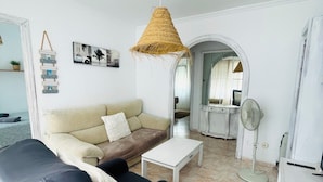 A living room with a sofa, a coffee table, a fan, and a hanging light fixture. - Cozy & Spacious apartment near the old town of Tarifa. (Tarifa)