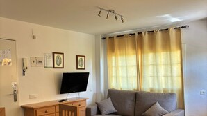 A living room with a sofa, two armchairs, a coffee table, a TV, and a wooden cabinet. - ISLANTUR BELLAMAR (Lepe)