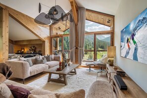 A cozy living room with a sofa, coffee table, and a large window offering a view of the outdoors. -  L'ARIONDAZ COURCHEVEL (Courchevel)