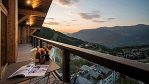 Varanda de madeira com vista para montanhas e uma cidade lá embaixo.