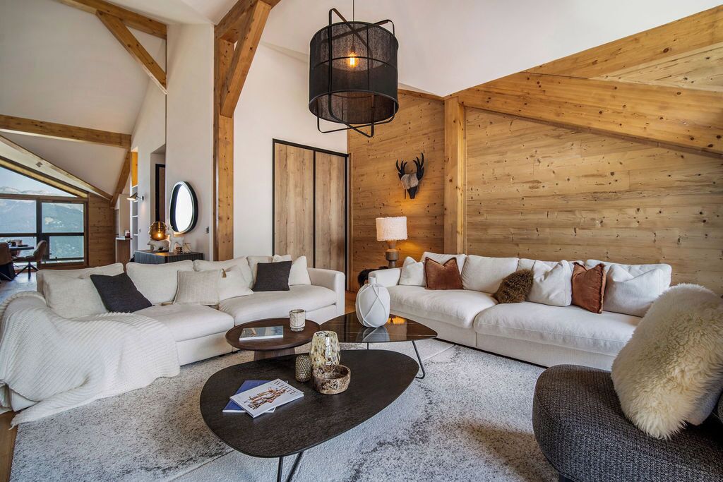 Un salon spacieux avec deux canapés blancs, une table basse et un plafond en bois.