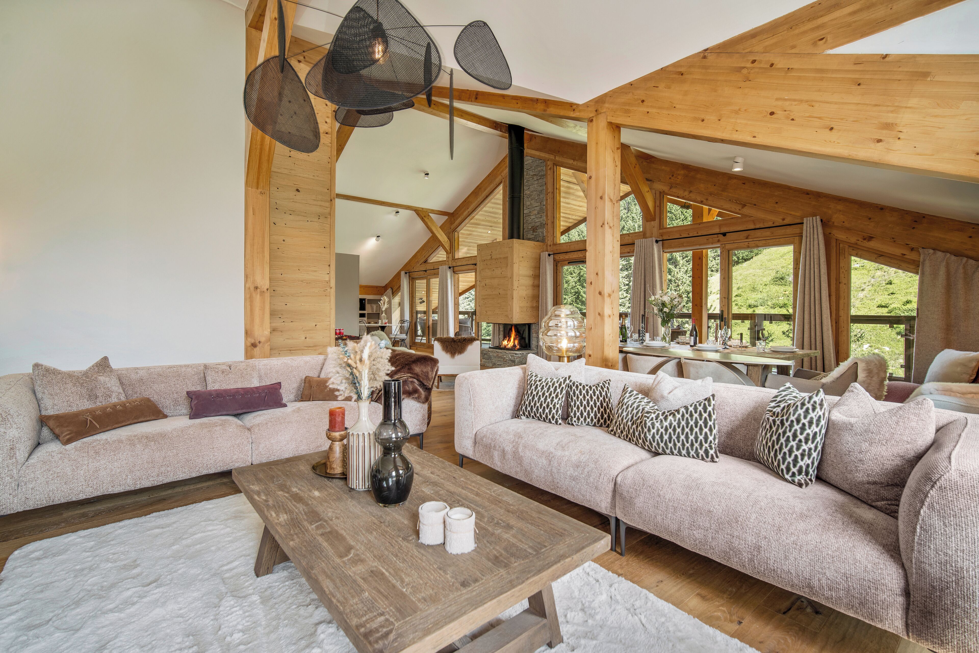 Un salón espacioso con techo de madera, ventanas amplias, chimenea y una zona de estar acogedora.
