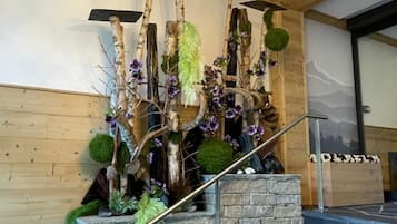 Una escalera con pared de piedra, vigas de madera y un adorno de ramas y flores.