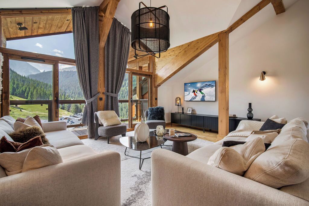 A spacious living room with a large window offering a mountain view, a cozy seating area with sofas and armchairs, and a modern pendant light.