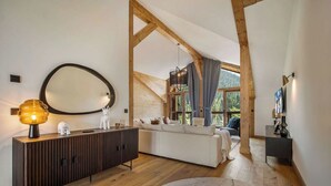 Uma sala de estar moderna com teto de madeira, um espelho redondo grande, um sofá branco e um armário de madeira.