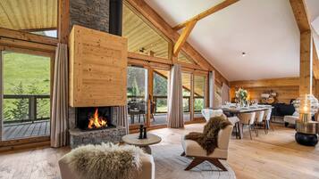 A spacious living area with a fireplace, large windows, and a dining area.