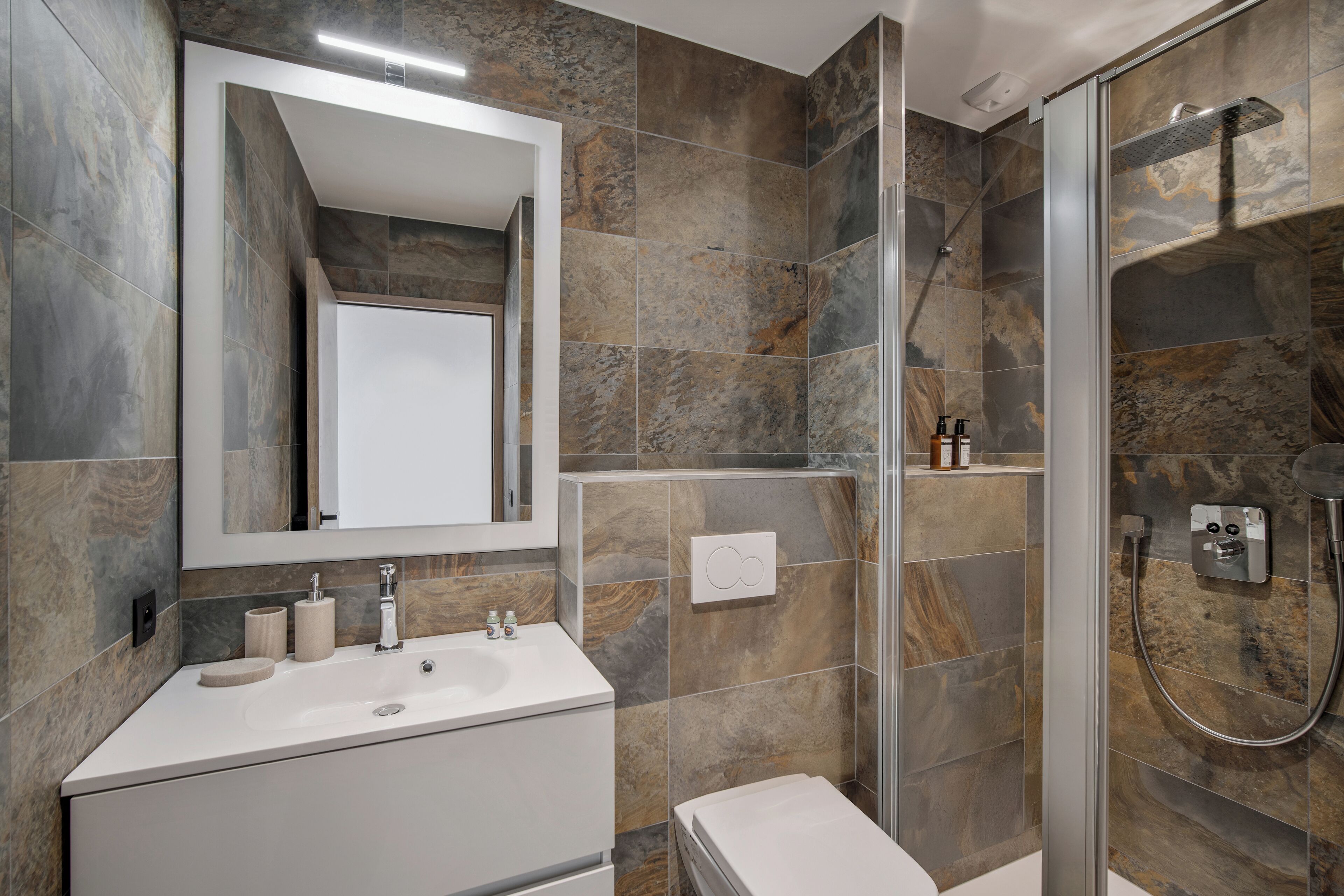 Une salle de bain avec un lavabo blanc, un miroir et une douche.