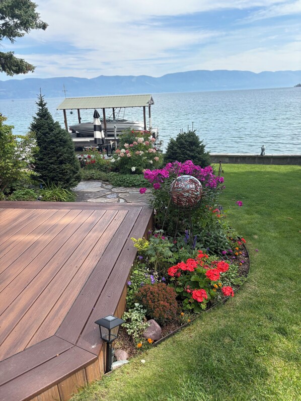 A wooden deck with a stone pathway leading to a gazebo by a lake.