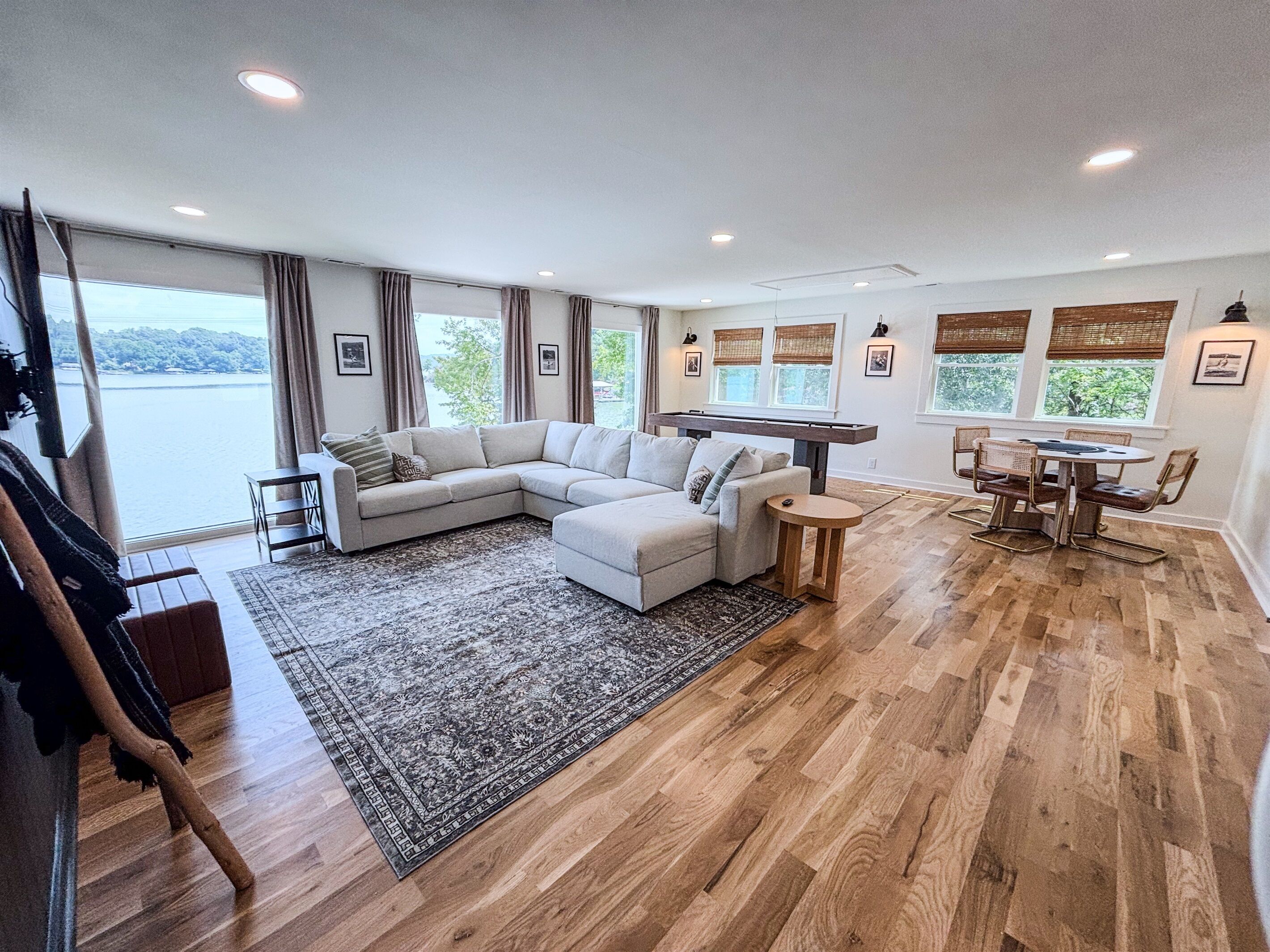 A spacious living room with a large sectional sofa, a dining table with chairs, and a view of the outdoors through large windows.