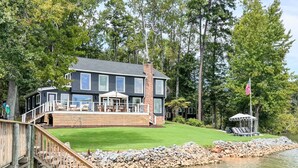 A modern two-story house with a deck, a stone retaining wall, and a flag. - The Belmont Lake Retreat -Sleeps 14! (Belmont)