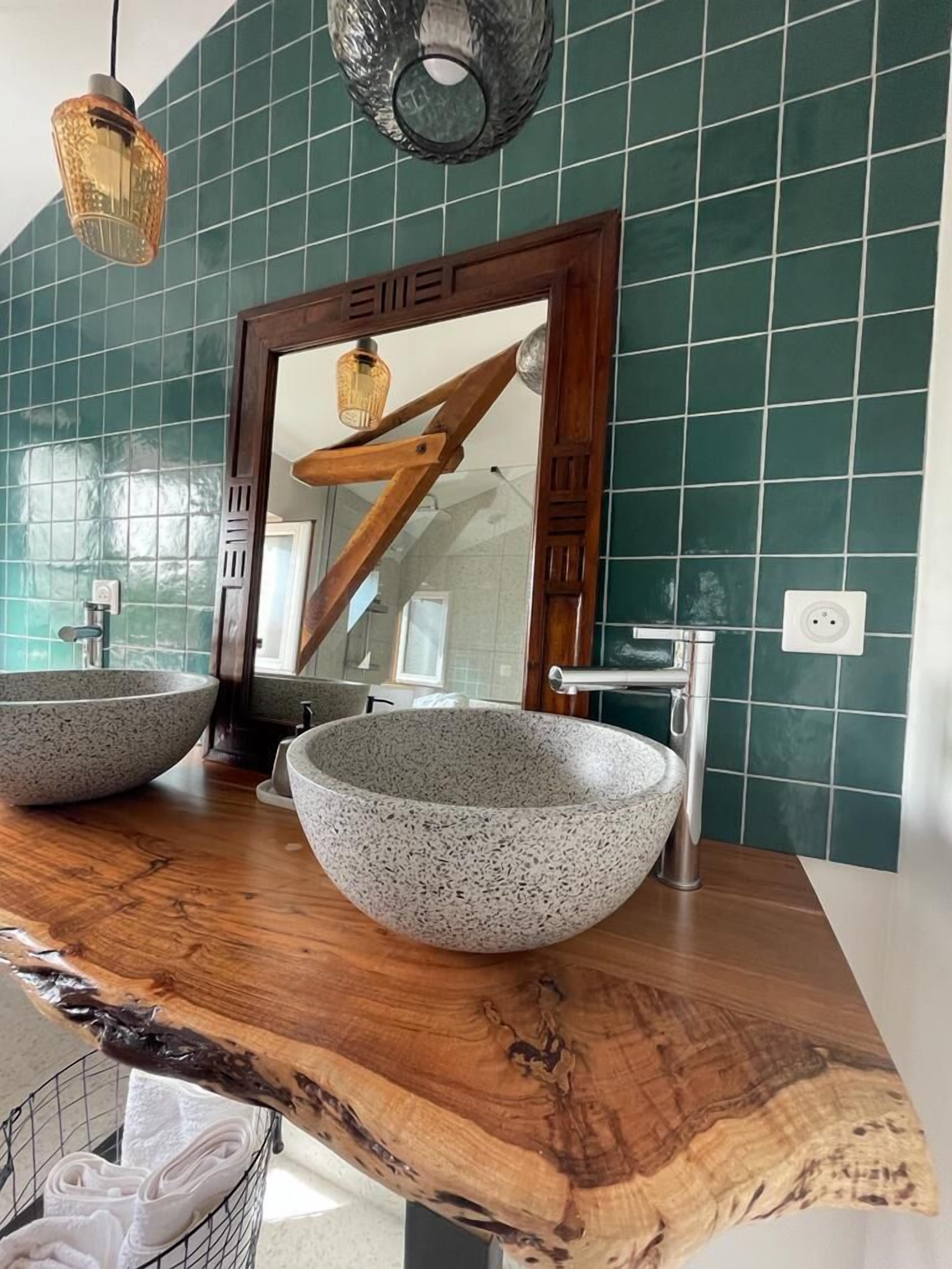Un baño con dos lavamanos de piedra, una encimera de madera y un espejo con marco de madera.