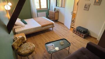 A loft-style bedroom with a bed, a small desk, a sofa, and a dining table.