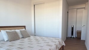 Ein Schlafzimmer mit einem Bett, einem Nachttisch, einem Teppich und einer Tür zu einem weiteren Raum.