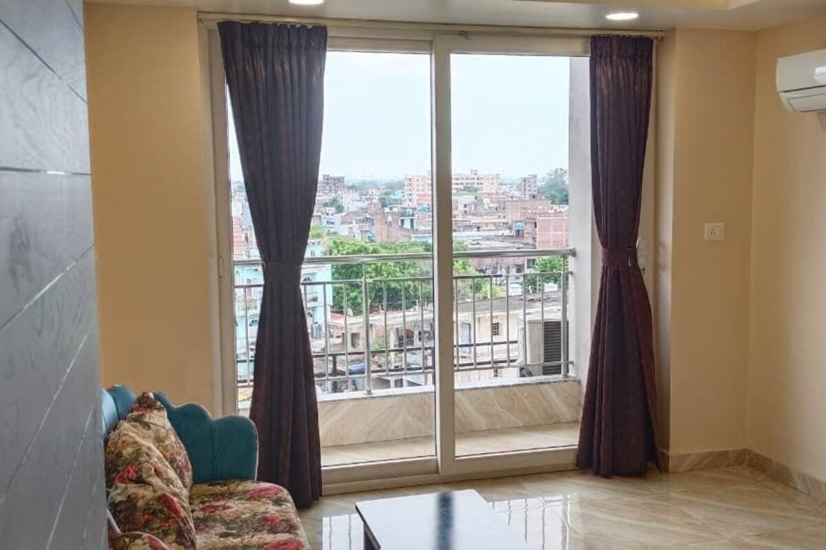 Una habitación con un ventanal grande, un sofá, una mesita de centro y un equipo de aire acondicionado.