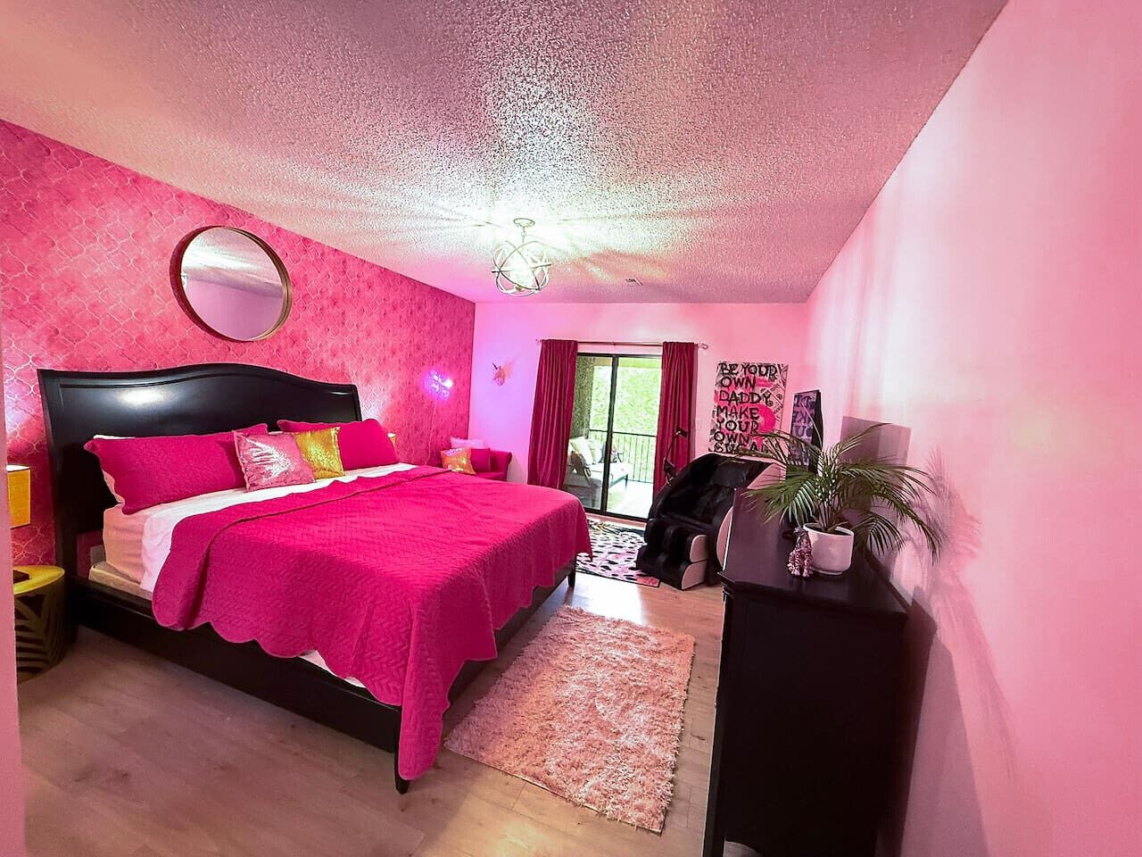 Un dormitorio con cama, un espejo redondo, una lámpara en el techo y una ventana con cortinas.