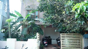 A narrow driveway leading to a gated entrance with a parked scooter and a red car. - Serene 3-bedroom house in Mysore (Mysore)