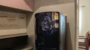 A kitchen with pink cabinets, a black refrigerator with floral design, and a wooden countertop. - Serene 3-bedroom house in Mysore (Mysore)