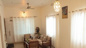 A spacious living room with a dining table, chairs, a sofa, and a ceiling fan. - Serene 3-bedroom house in Mysore (Mysore)