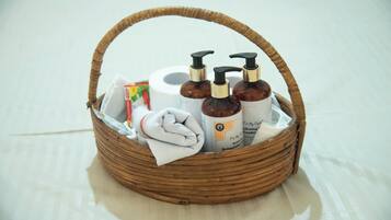 Cestino di vimini con articoli da bagno, fazzoletti e un asciugamano piegato.