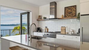 Una cocina moderna con una isla grande, electrodomésticos de acero inoxidable y vistas al mar.