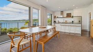 Una cocina moderna con una isla grande, un comedor con mesa y sillas de madera, y un balcón con vistas panorámicas.