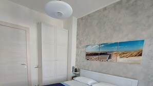 Quarto com uma cama grande, um guarda-roupa branco, mesa de cabeceira e um quadro na parede.