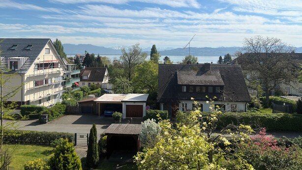 A residential area with houses, a garage, and a view of mountains in the distance.