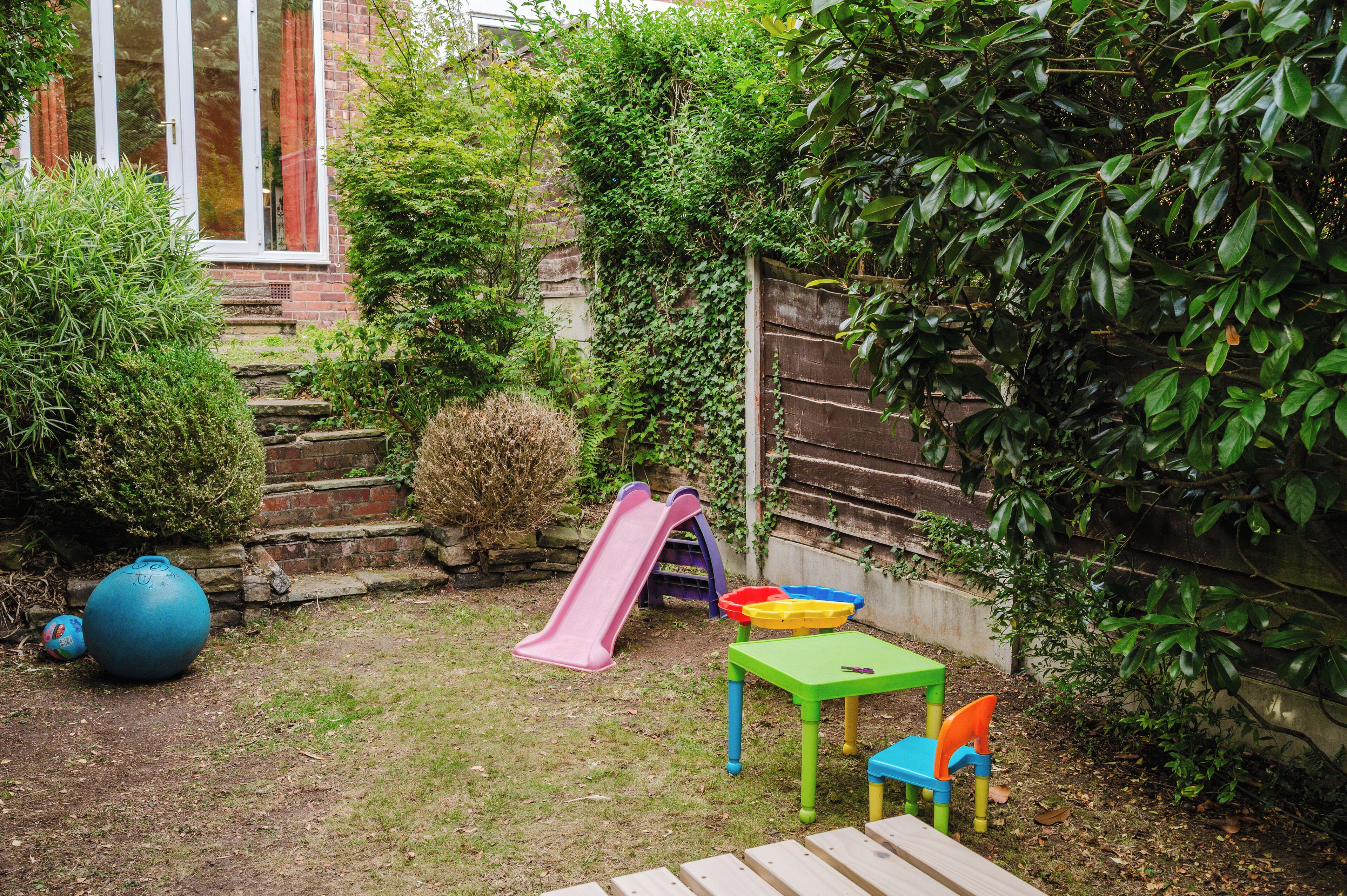 A backyard with a slide, a table, and a ball.