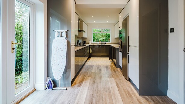 Una cocina moderna con una isla grande, muebles oscuros y vistas al verdor exterior.
