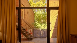 Una stanza con un letto, una scala e vista su un edificio in mattoni e alberi.