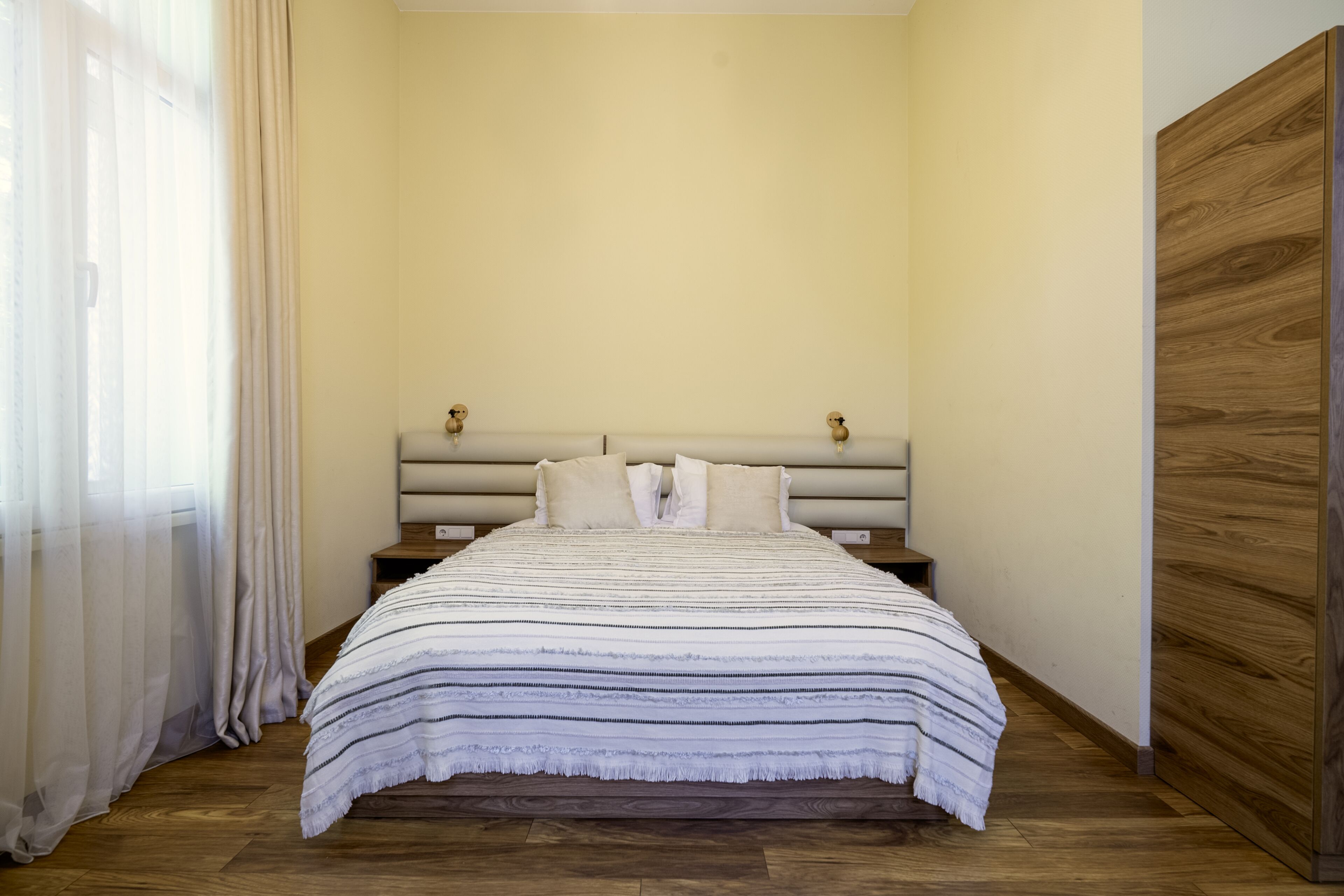 A bedroom with a bed, wooden headboard, and a nightstand.