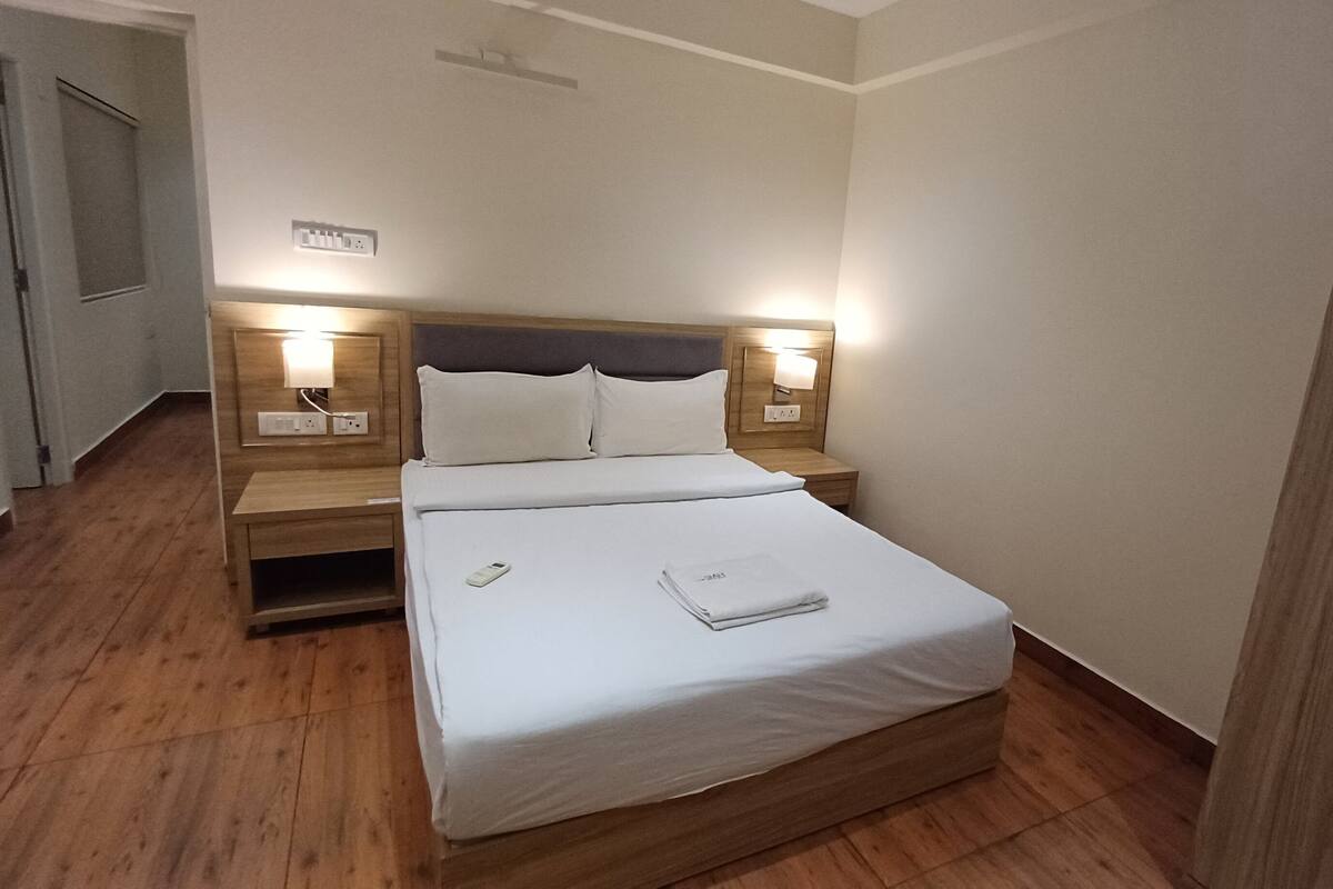 A neatly made bed with white linens, two bedside tables with lamps, and a wooden headboard.