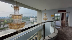 Interior de hotel con balcón, candelabros y vista a una calle y edificios.