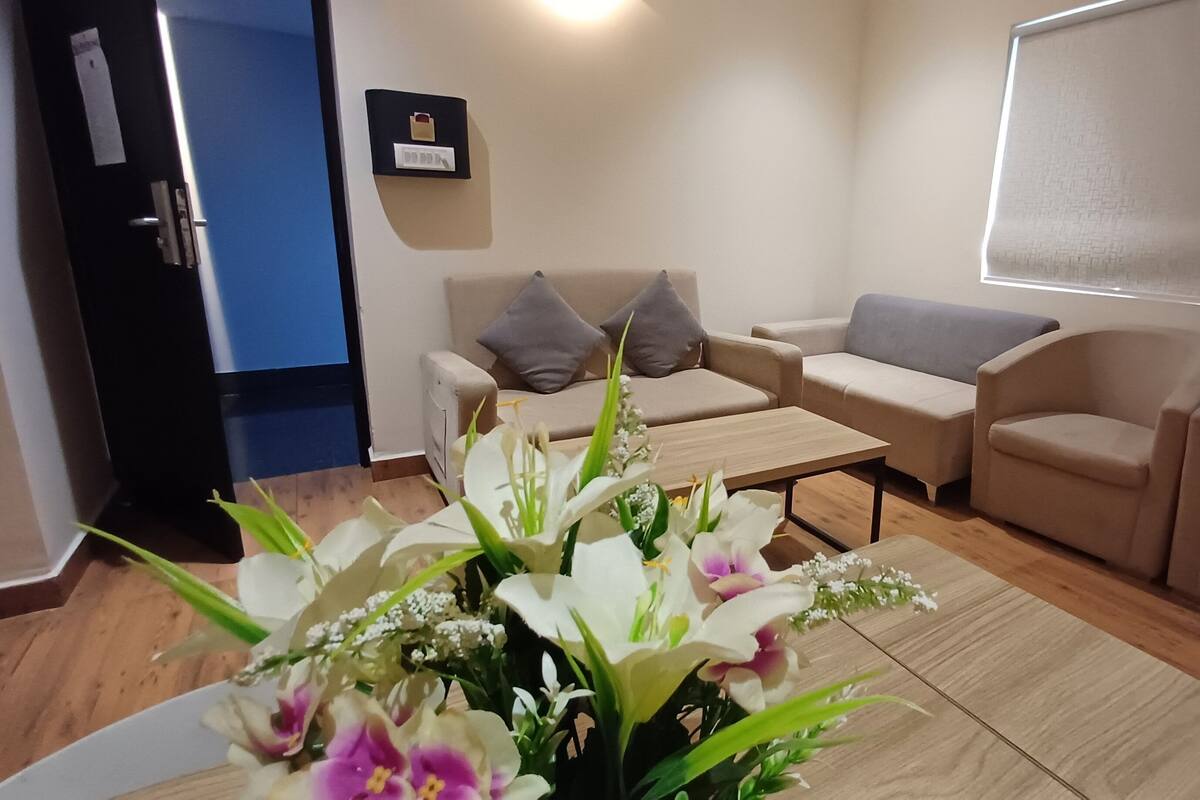 A living room with a sofa set, a coffee table, and a floral arrangement.
