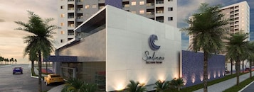 Um hotel moderno com uma fachada de vidro e exterior bem cuidado, exibindo um logotipo em destaque.