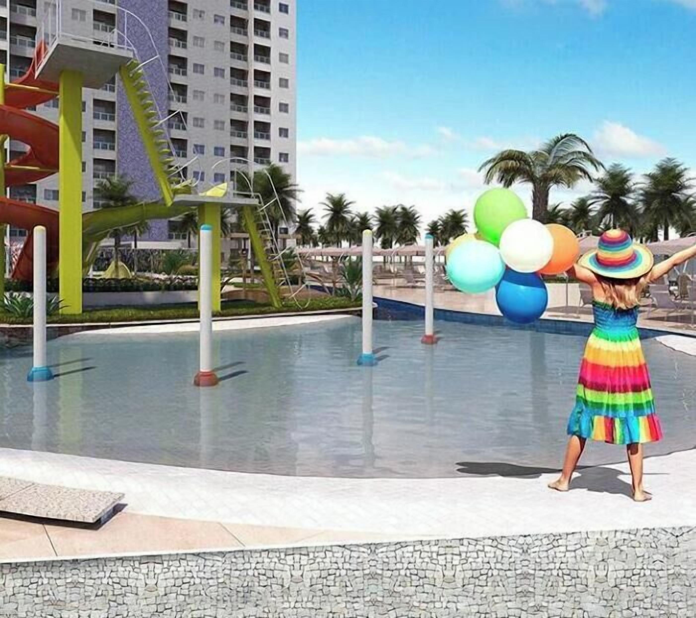 Un resort con parque acuático, un edificio alto y una persona sosteniendo globos.