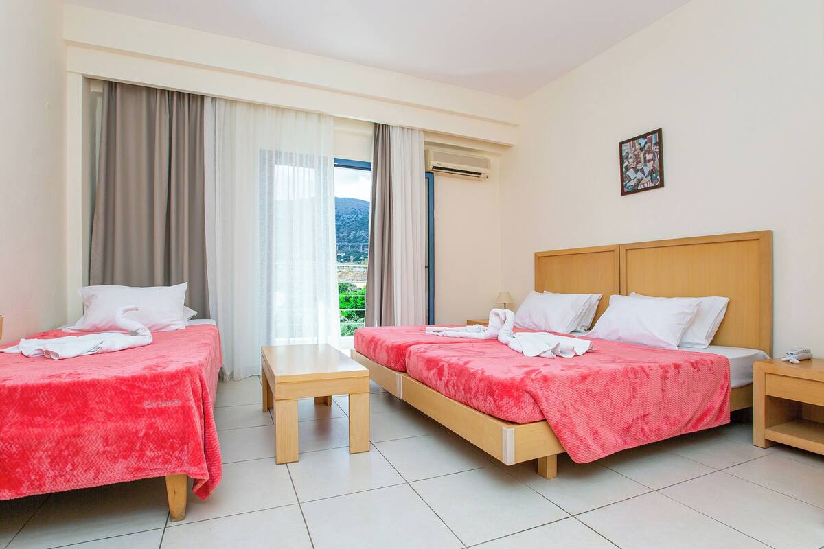 Une chambre d’hôtel avec deux lits, une petite table et une vue sur l’extérieur.